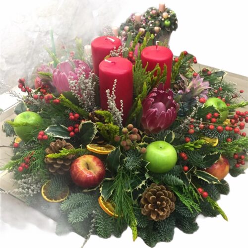 Centro tavola con candele rosse eletti naturali fiori tropicali  e frutta secca